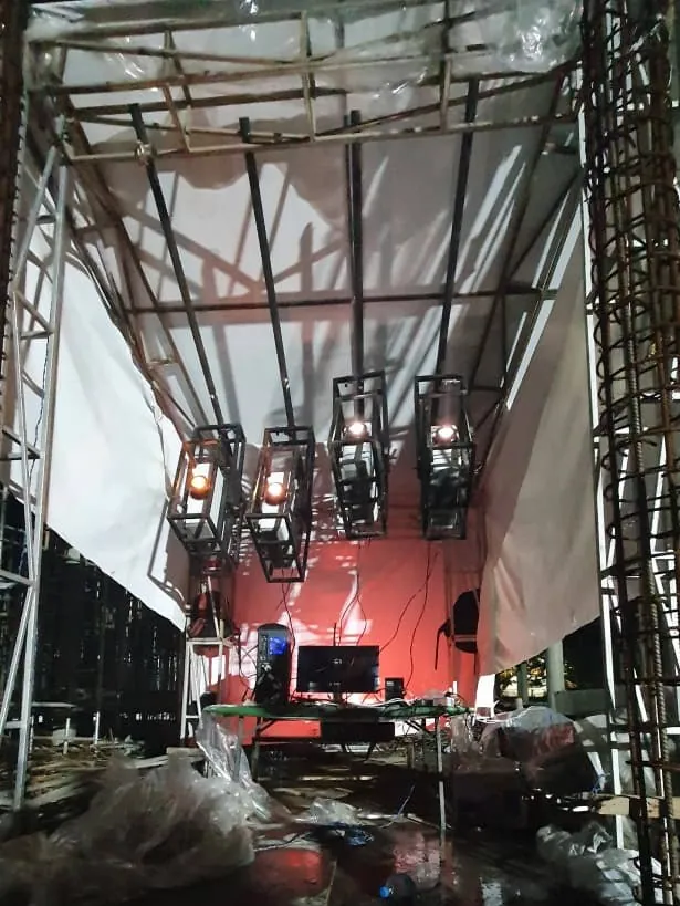 The inside of the projection tent: hung projector cages above a table with a computer and monitor, lit red.