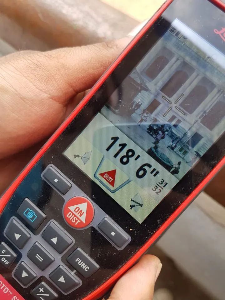 Leica DISTO S910 display reading 118 feet 6 31/32 inches, with the facade visible in its viewfinder.