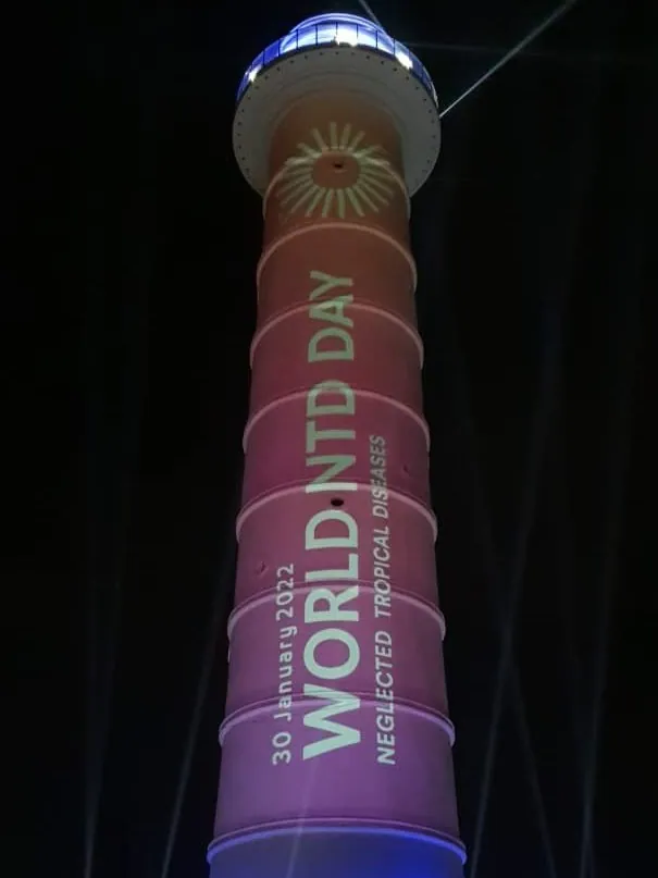 The tower lit pink and blue with the text World NTD Day, Neglected Tropical Diseases, 30 January 2022 and a sun emblem near the top.