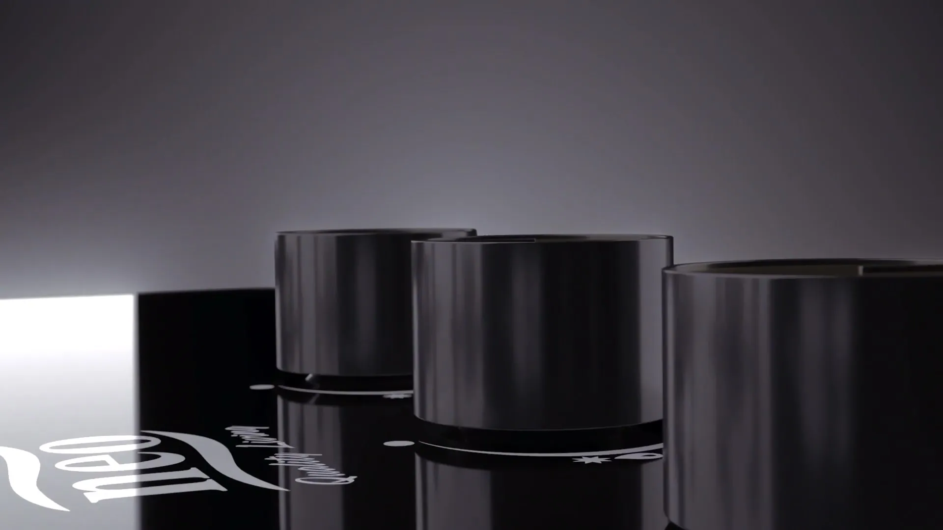 Rendered close-up of three black knobs on a glossy black glass hob with the NEO mark reflected in the surface.
