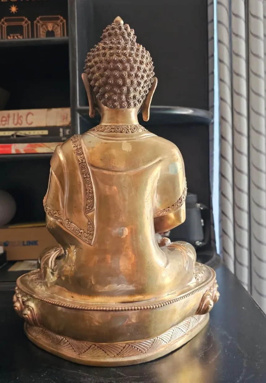 Back view of the brass Buddha showing the robe folds, a decorated border and the head curls.
